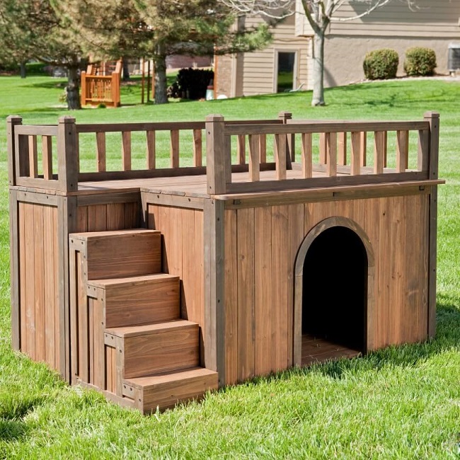 Casinha de cachorro de madeira grande com deck na cobertura.