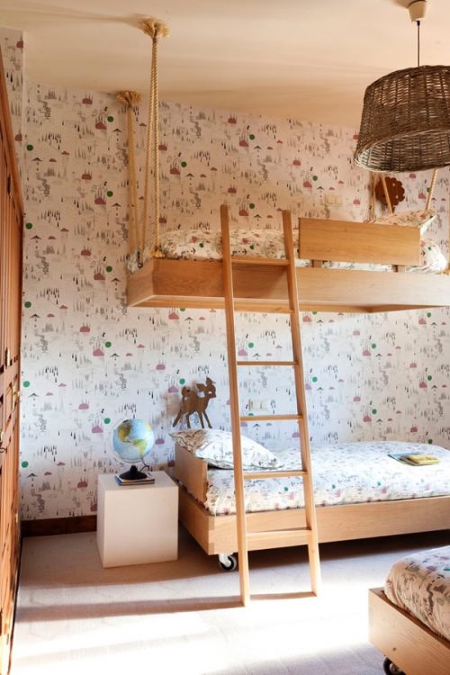 Quarto com beliche de madeira criativo com a cama de cima pendurada por cordas.