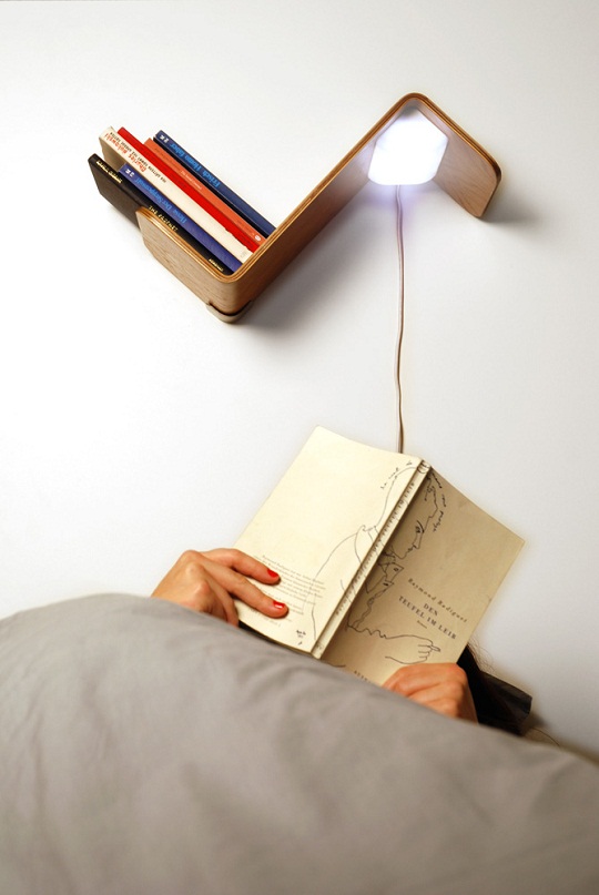 Prateleira de madeira para livros com luminária embutida.
