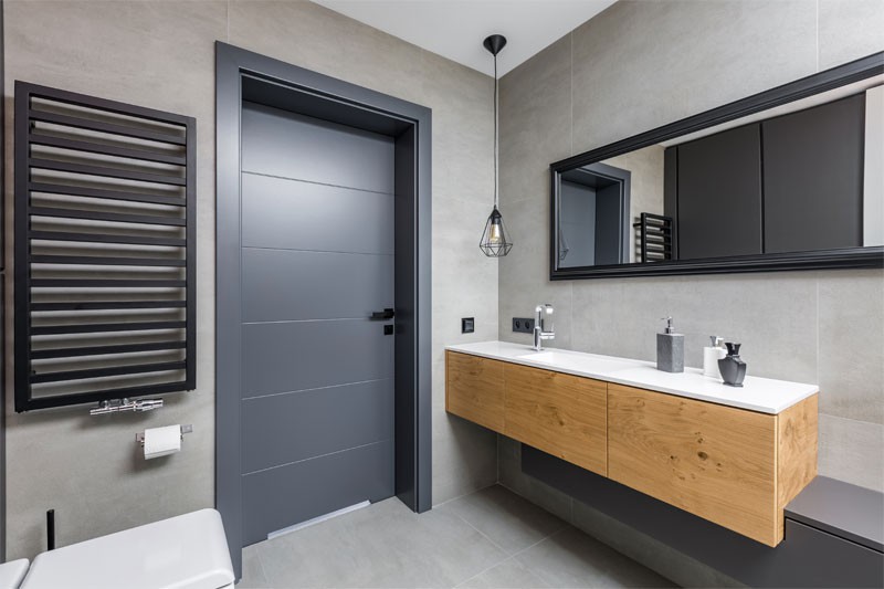 Banheiro com porta de madeira cinza.