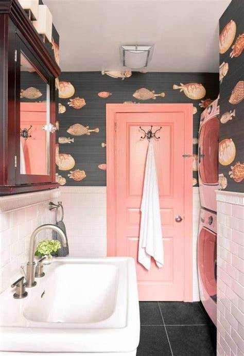 Banheiro com porta rosa coral combinando com papel de parede cor pêssego.